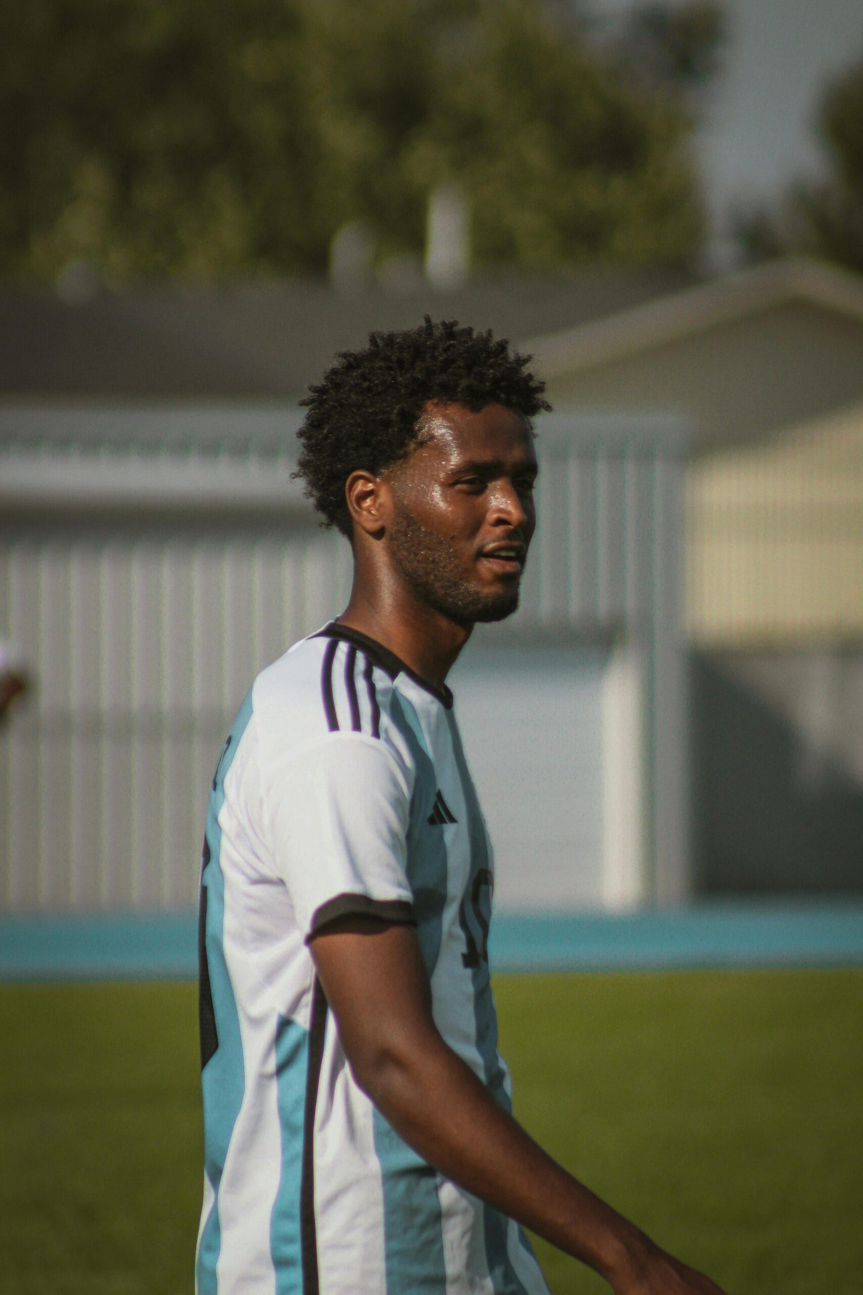 A focused soccer player during a daytime match on a grass field.